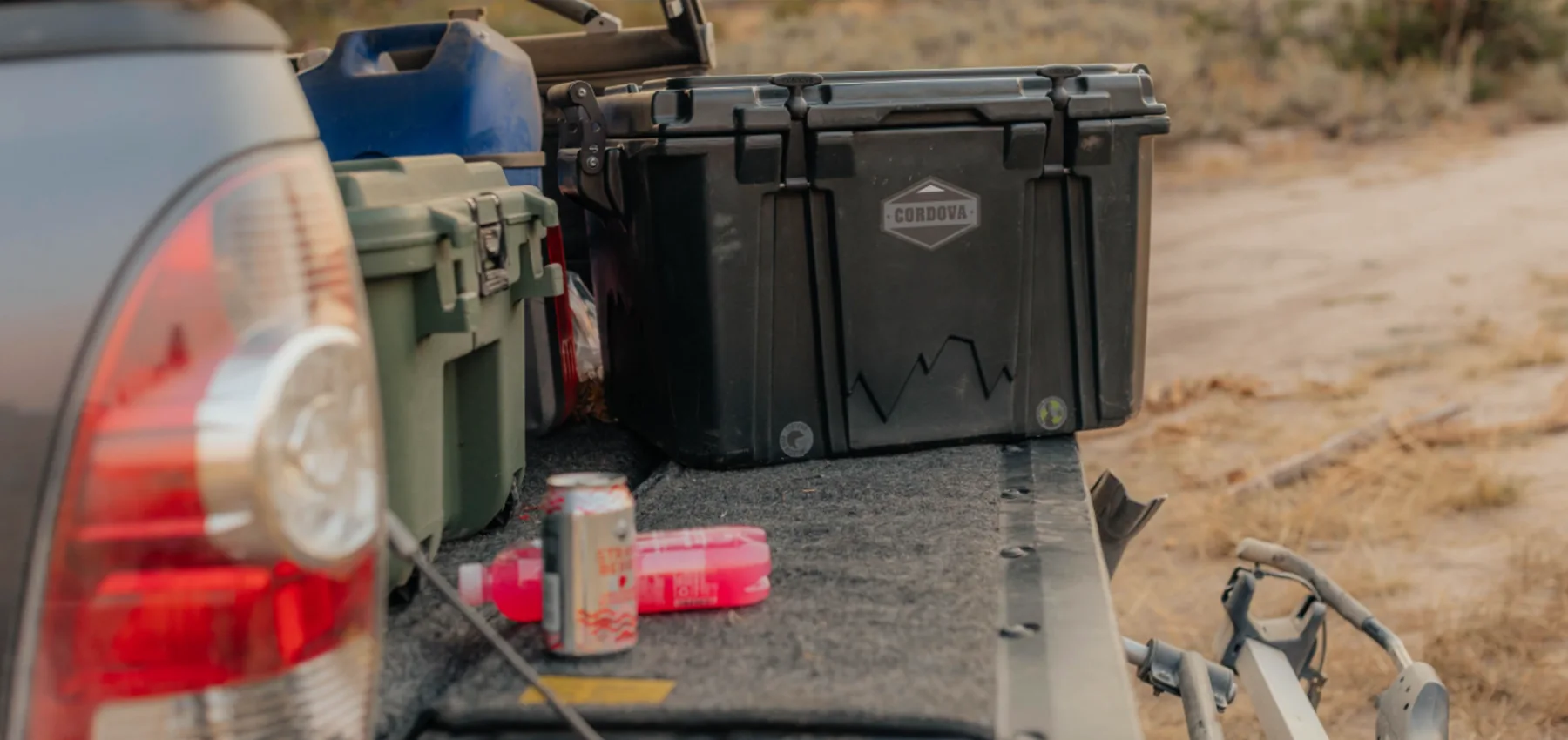 Black Pelican cooler on a truck bed with various items in an outdoor setting
