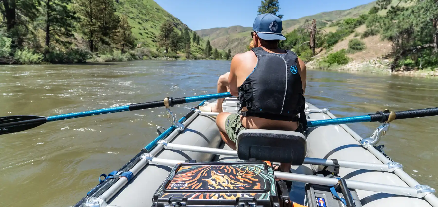 Person rafting on a river with mountains in the background