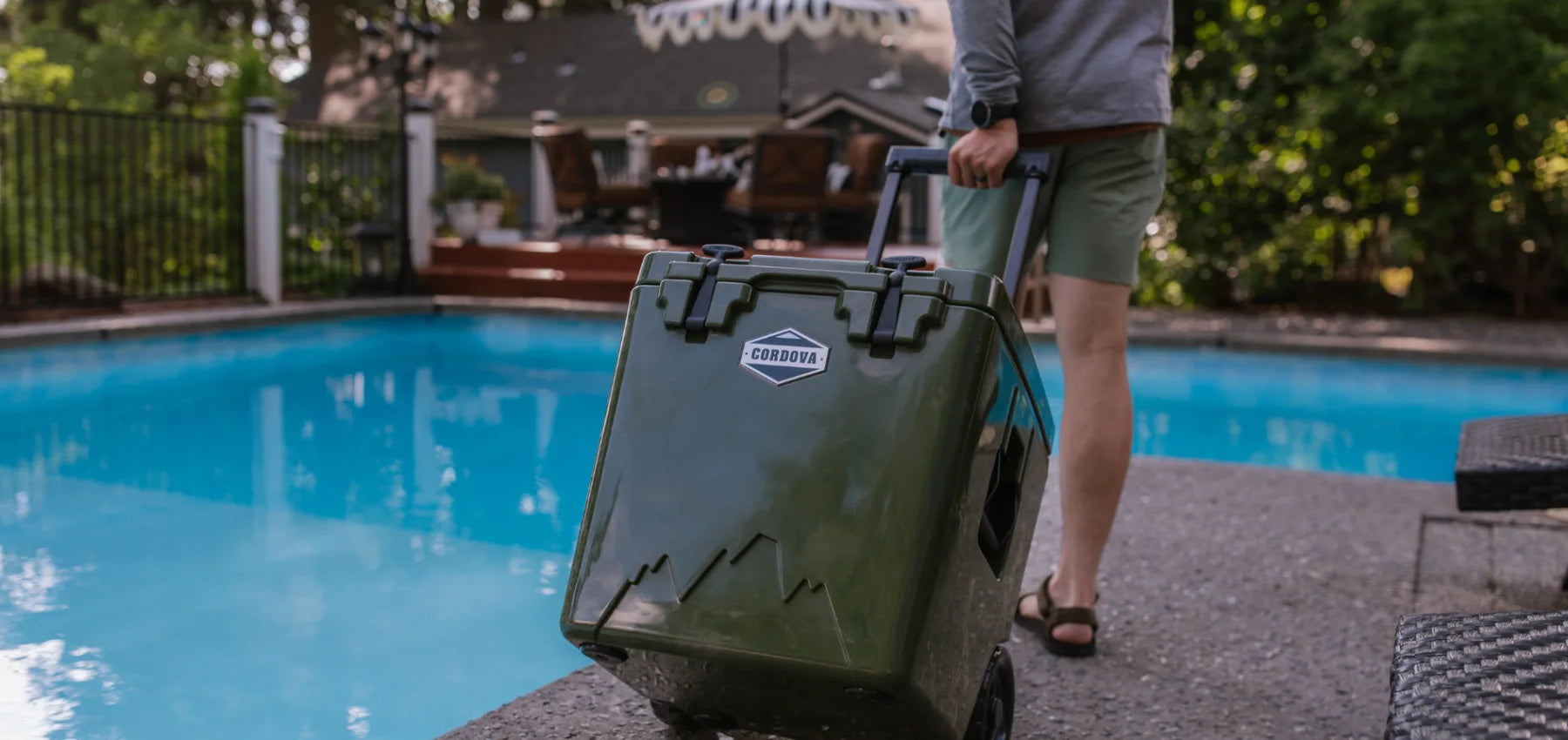 Person holding a wheel cooler by a poolside